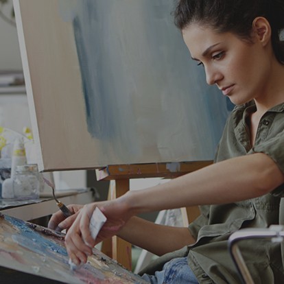 A woman at an easel, painting with oil colours