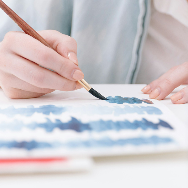 A woman layering washes of blue paint to experieme