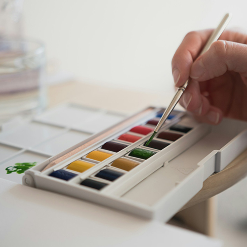 Close up of an artist applying half pan paint from